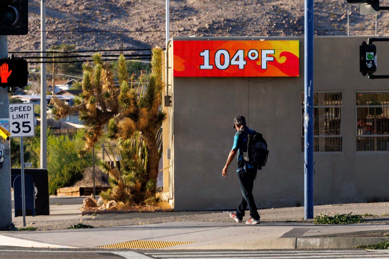 JOSHUA TREE, CA - JUNE 5, 2024: Triple digit temperatures ascend on the high desert as a pedestrian walks from a bus stop past the Joshua Tree library digital temperature thermometer on JUNE 5, 2024 in Joshua Tree, California. This week, the state's inland communities will feel the most intense temperature spikes from the high pressure ridge, or heat dome, parked over California.(Gina Ferazzi / Los Angeles Times via Getty Images)